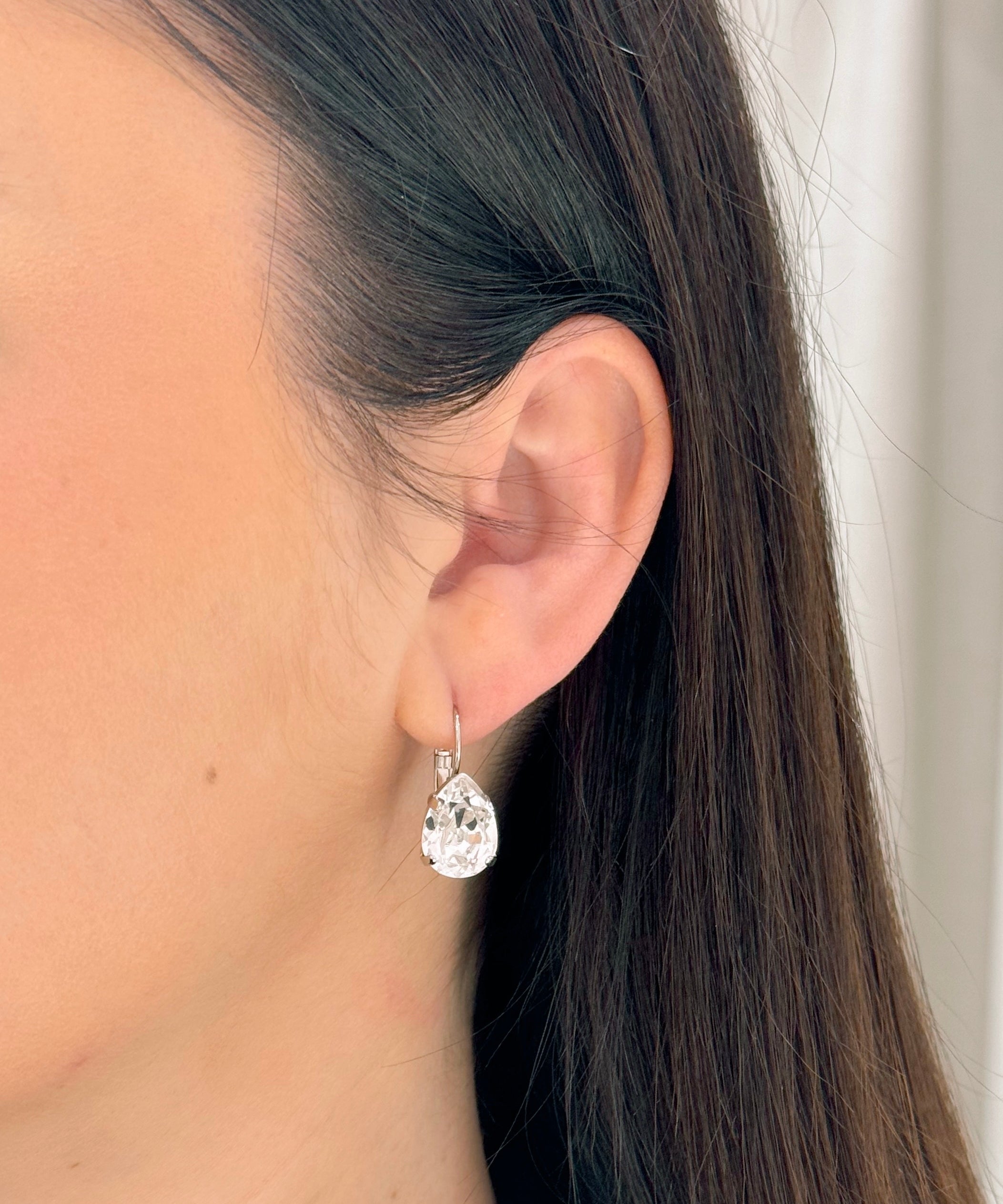 Close-up of a person wearing a teardrop-shaped earring with a blurred background