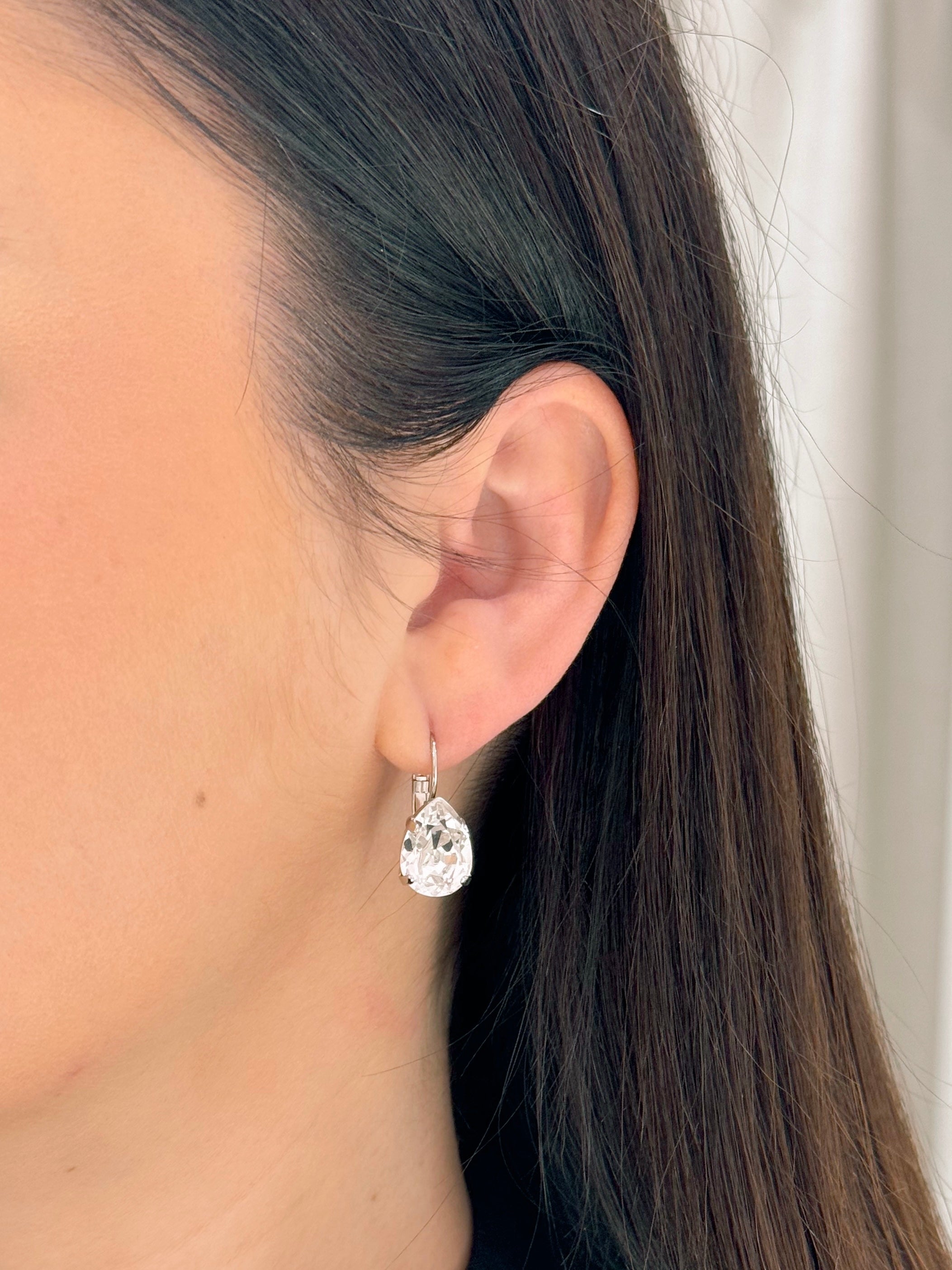 Close-up of a person wearing a teardrop-shaped earring with a blurred background
