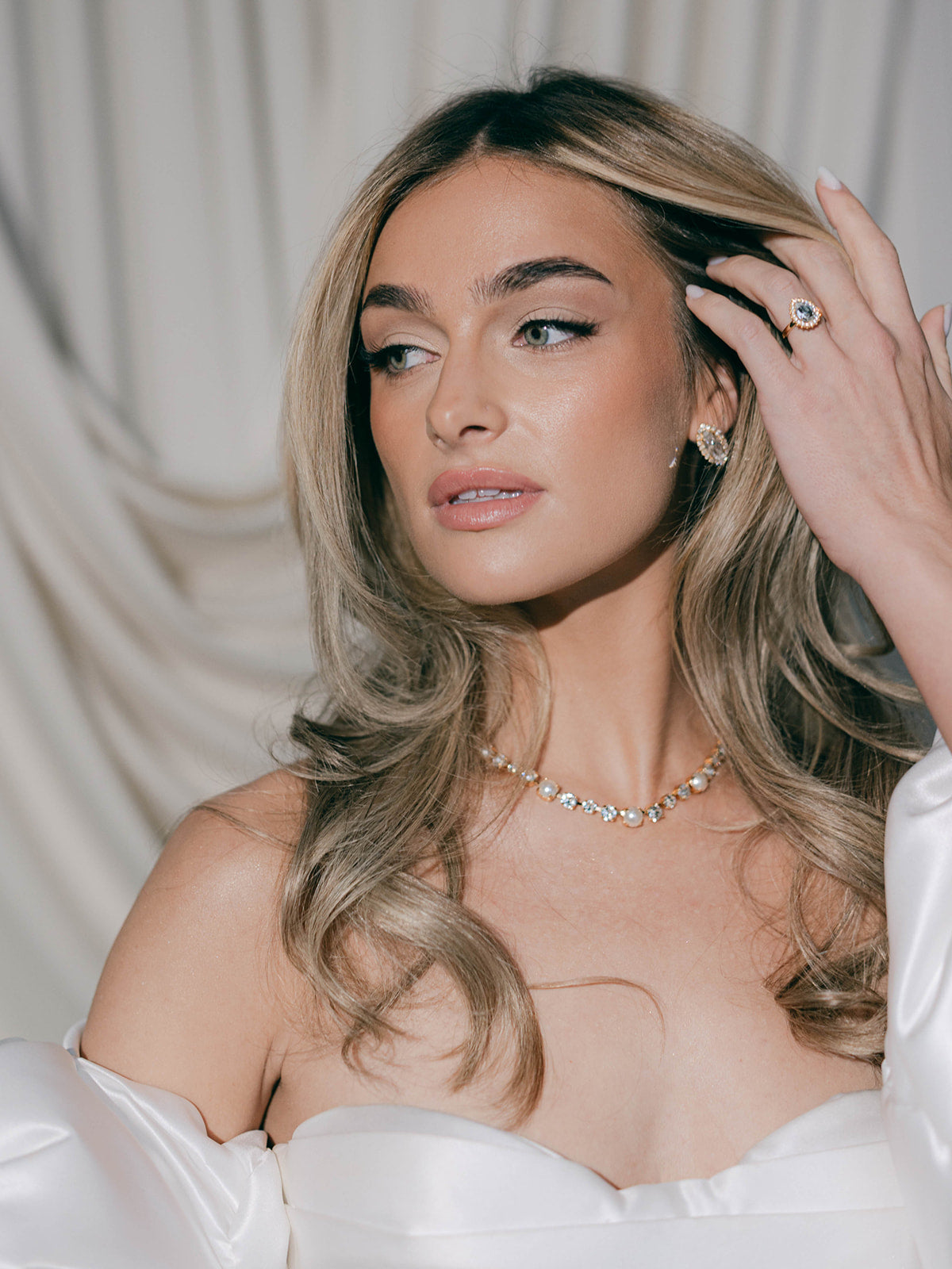 Woman with styled hair and jewelry by sarah gauci against a neutral background