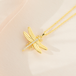 A gold-plated sterling silver necklace with a cubic zirconia pendant shaped like a dragonfly, displayed on a pale background.
