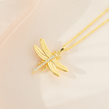 A gold-plated sterling silver necklace with a cubic zirconia pendant shaped like a dragonfly, displayed on a pale background.