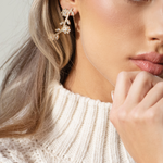 A woman wearing The Rose Earrings, which feature a delicate, graduated pattern of petite blooms, with 18K gold or rhodium plating and hypoallergenic titanium posts.