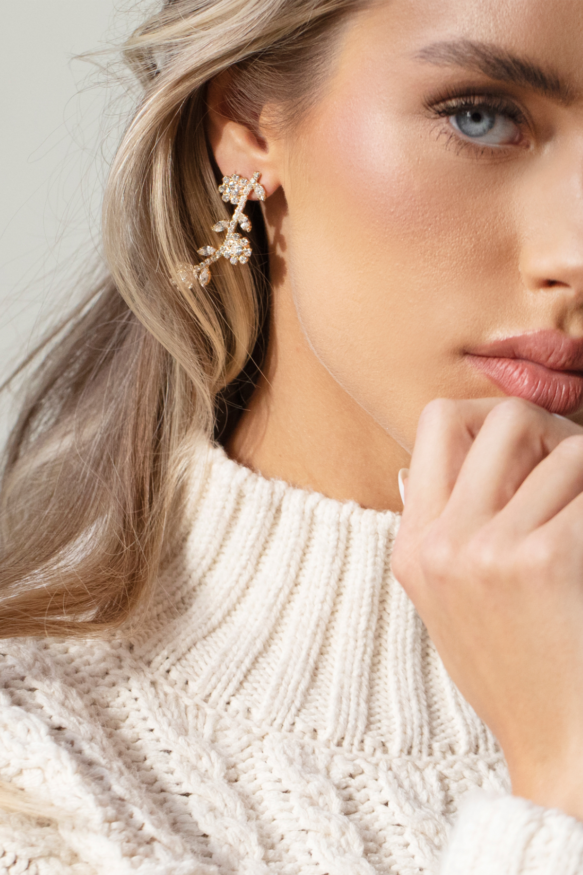 A woman wearing The Rose Earrings, which feature a delicate, graduated pattern of petite blooms, with 18K gold or rhodium plating and hypoallergenic titanium posts.