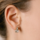 A close-up image of a woman's ear wearing a silver stud earring with a clear crystal.