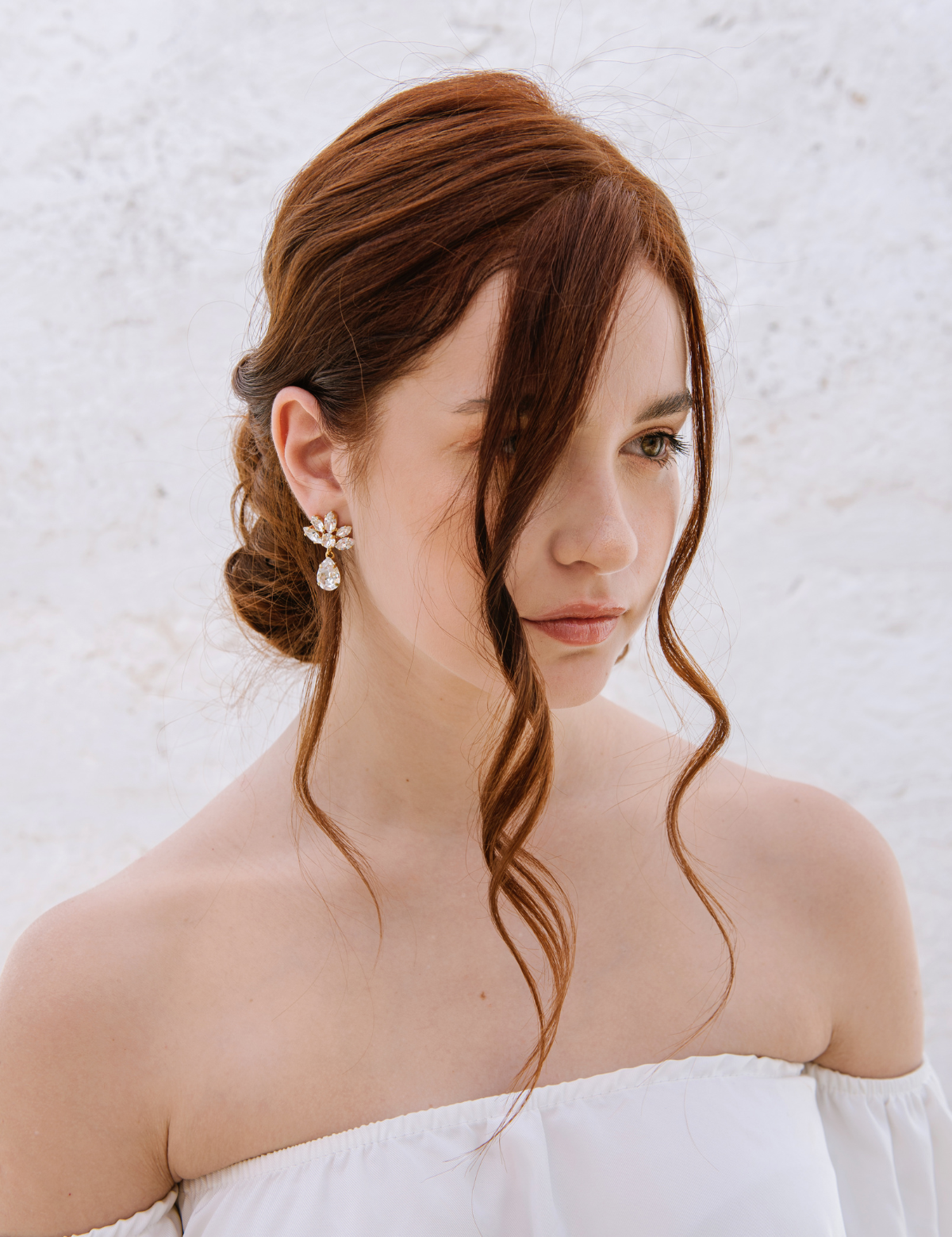 A woman with a soft low-tousled bun wearing The Muse Earrings, which feature cascading crystals. The earrings are 18K gold plated or rhodium plated in Puglia, Italy. Wedding in Italy, Italy Wedding Jewelers, Sposa, 