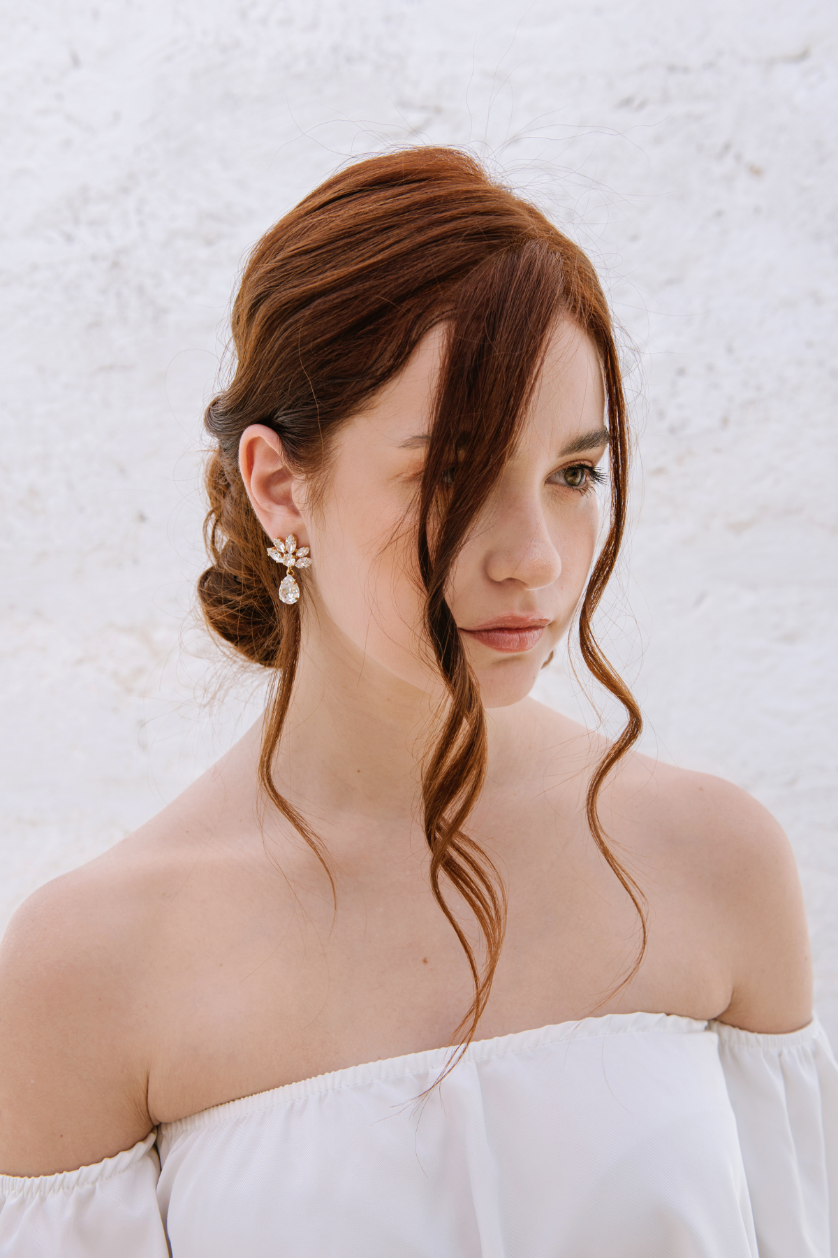 A woman with a soft low-tousled bun wearing The Muse Earrings, which feature cascading crystals. The earrings are 18K gold plated or rhodium plated in Puglia, Italy. Wedding in Italy, Italy Wedding Jewelers, Sposa, 
