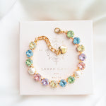 A gold-plated bracelet adorned with multicolored crystals set in a star pattern, presented on a white card with 'SARAH GAUCI' written at the top.