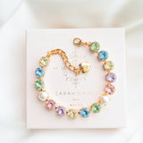A gold-plated bracelet adorned with multicolored crystals set in a star pattern, presented on a white card with 'SARAH GAUCI' written at the top.